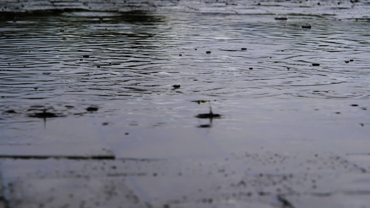 gotas de lluvia cayendo en la piscina el día con un clima miserable, zoom de ángulo bajo