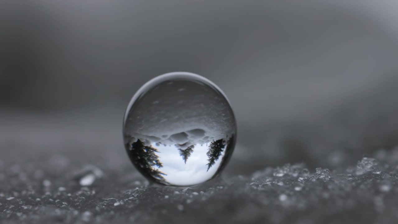 Die Kamera zieht den Fokus, macht umgedrehte Bäume in einer Glaskugel schärfer, um Details auf Schneekörnern zu zeigen.