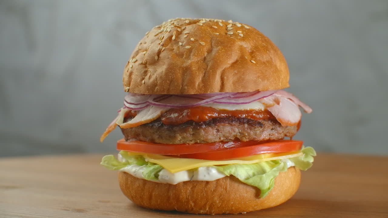 una hamburguesa grande y sabrosa con carne, cebollas, verduras, queso derretido y lechuga.