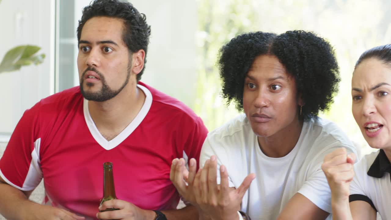 Diverse friends reacting to off-screen play, man gesturing, woman shouting, beer bottle visible