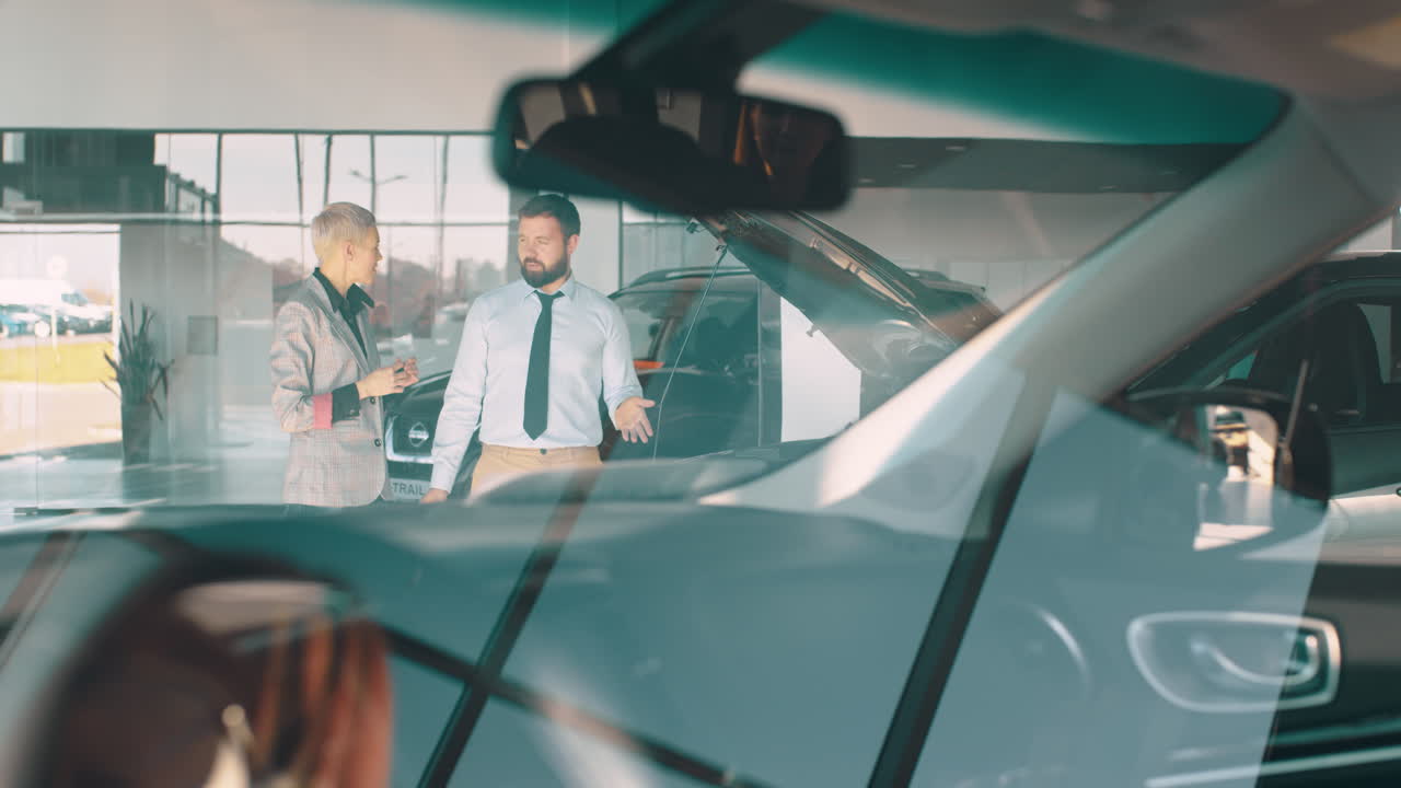 vendedor de automóviles discutiendo el automóvil con el cliente en la sala de exposiciones