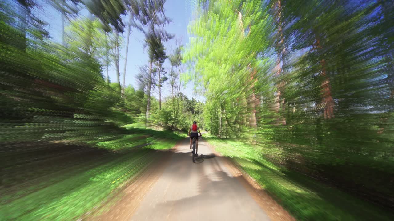 The rear view of the female cyclist riding a bicycle in the Divoka Sarka natural reserve in Prague on a sunny summer day
