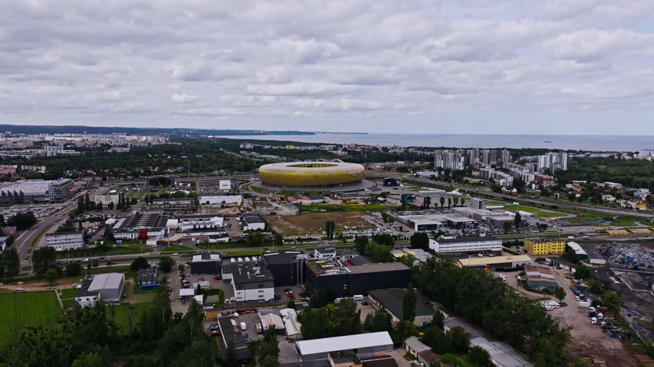 Aerial panorama, Gdansk arena framed by vast cloudy skyline and urban zone