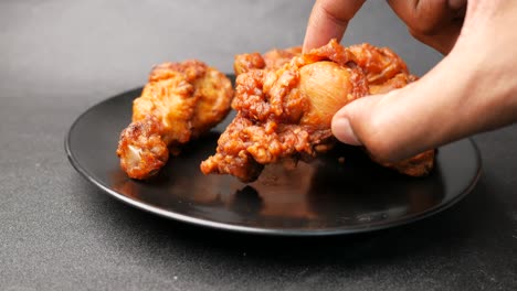 la mano recogiendo un pedazo de pollo frito