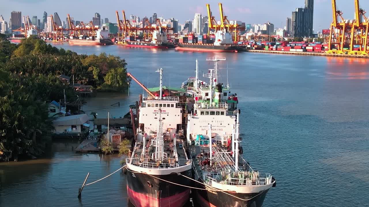 View of boats docked in Bangkok with river and structures in background
