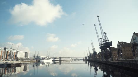 london docklands harbor scene with cranes and yacht