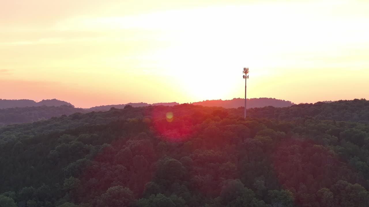 숲 속 의 언덕 에서 해 가 지는 때 셀 타워 를 돌고 있는 공중 사진