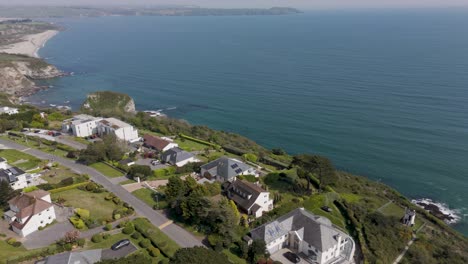 aerial view of contemporary luxury cliffside homes with private gardens overlooking a sun-lit ocean horizon, capturing upscale coastal living and architectural elegance