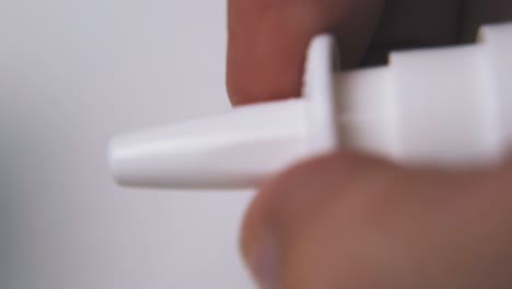 persona abre y presiona el aerosol nasal en un fondo claro