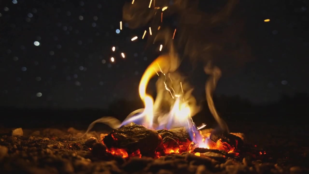 熾熱的餘燼在碎石地上向上升騰火花和煙霧，在星空下。
