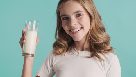 teenage caucasian girl in pijamas drinking milk from a glass and smiling.