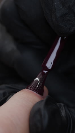 la aplicación de esmalte de uñas púrpura oscuro