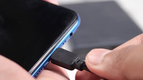 enchufando el teléfono a la mano en el cable de carga