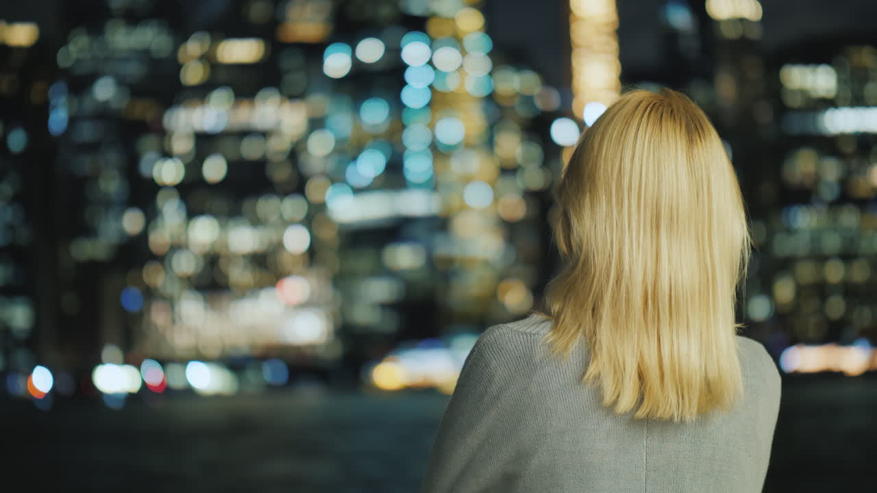 mujer rubia mirando la vista trasera de la ciudad nocturna