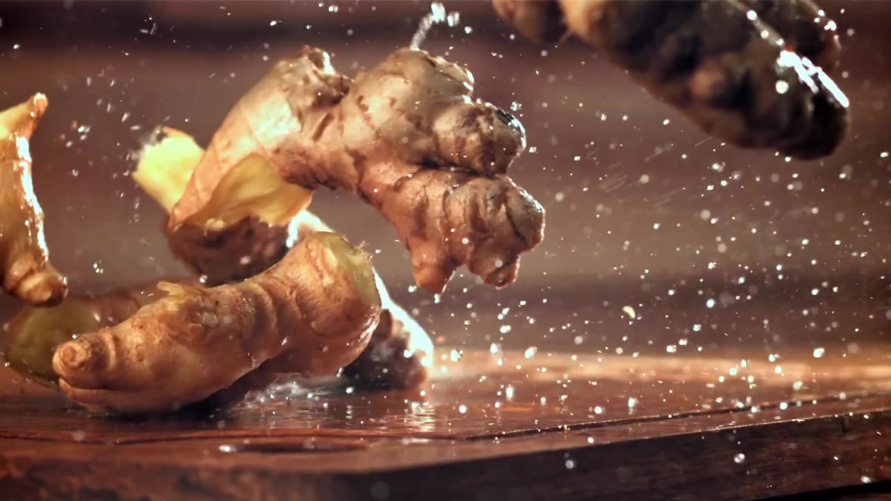Fresh Ginger Roots Falling and Splashing on Wet Wooden Board