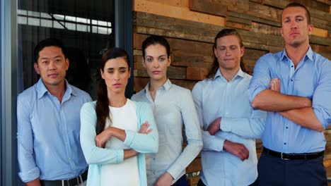 Confident-business-executives-standing-with-arms-crossed-in-office