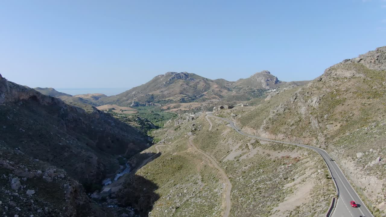 High aerial panoramic view of road, arid landscape, mountains and sea