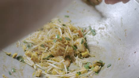 white asian noodle, bean sprout and shrimps while being cooked and stir fried in the pan preparing to make pad-thai