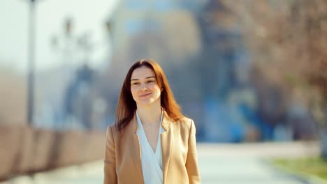 young brunette woman is walking along the spring street, the girl is happy. portrait view. circular motion of the camera.