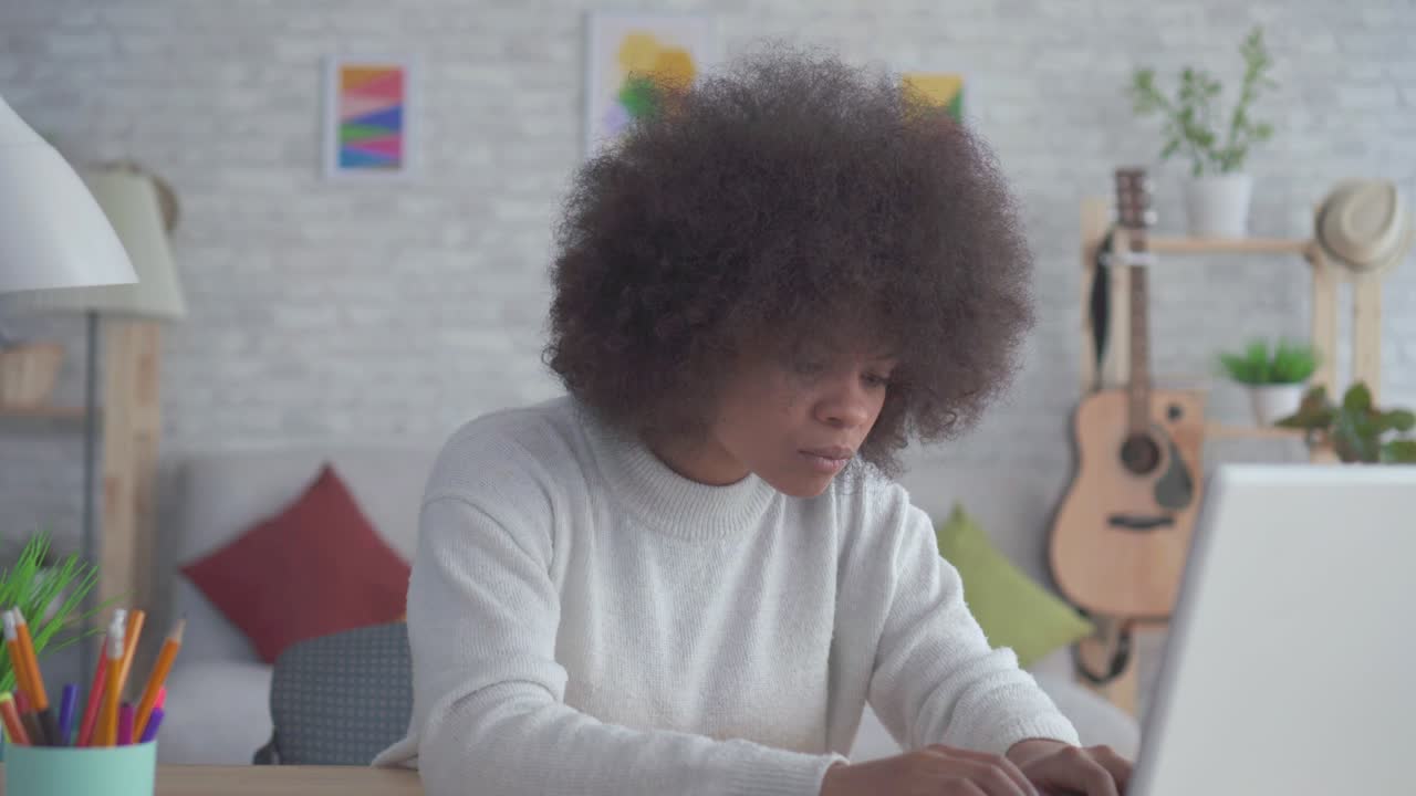 Portrait beautiful african american woman with an afro hairstyle uses a laptop at home