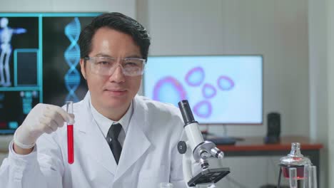 young asian male research scientist looking  glass test tube and warmly smiles into the camera