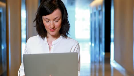 Ejecutiva-Femenina-Usando-Laptop-En-El-Pasillo