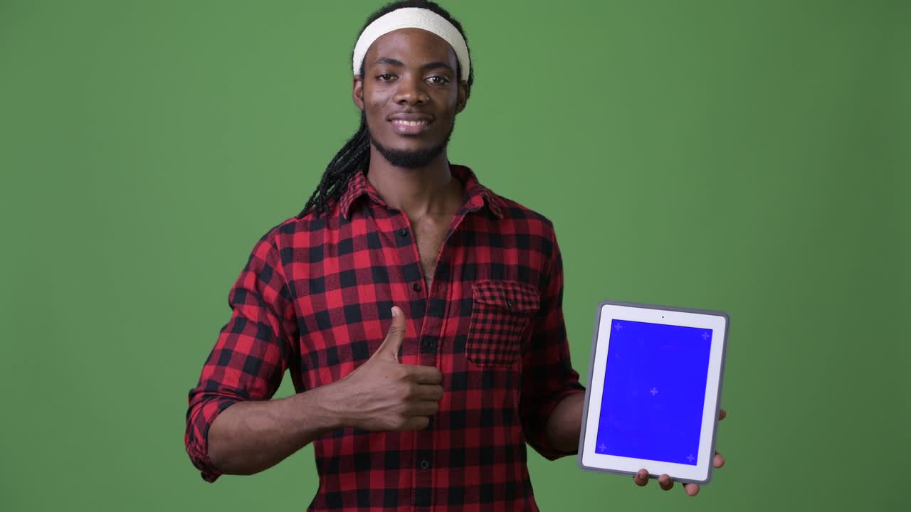 Young handsome African man with dreadlocks against green background