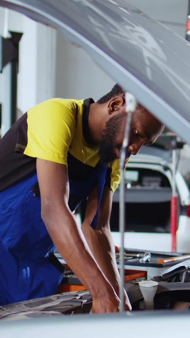 Vertical video Technician replaces car engine in garage