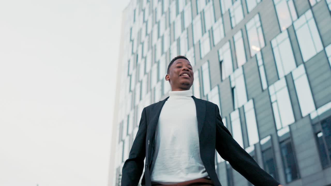 alegre, positivo hombre vestido con traje se encuentra afuera frente al edificio de vidrio de la compañía, corporación, trabajador de oficina recibió buenas noticias feliz bailando agitando las manos satisfacción promoción, salario