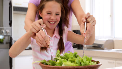 Mutter-Zeigt-Ihrer-Süßen-Tochter,-Wie-Man-Einen-Salat-Mischt