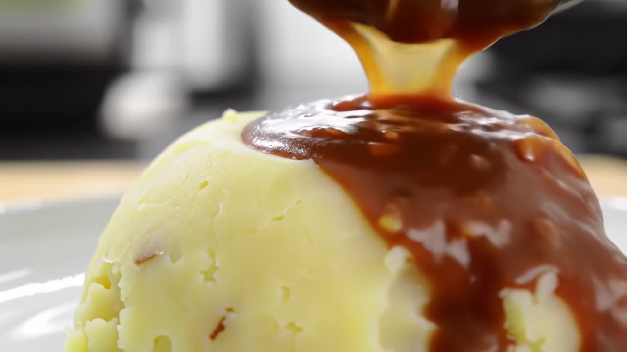 Delicious Close-Up of Creamy Mashed Potatoes Being Topped with Rich Gravy for a Flavorful and Tempting Culinary Experience