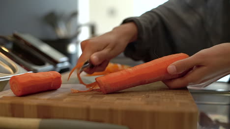 close up of female hands peeling a carrot