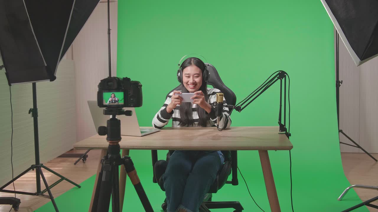 Donna in live streaming di un gioco mobile su schermo verde