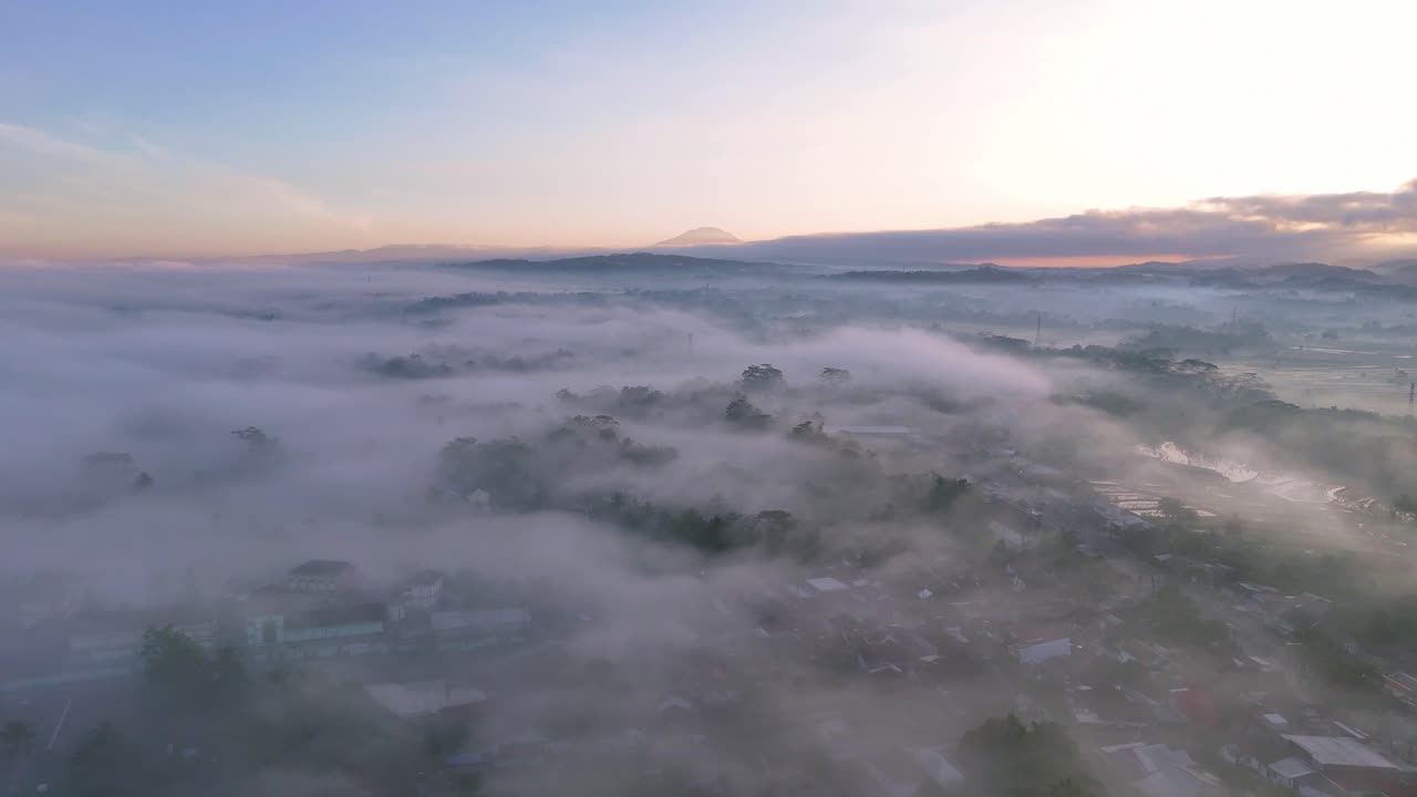Aerial morning view of a mist-shrouded countryside. Houses and trees are faintly visible through the haze