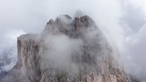 mountain peak covered in clouds by seceda ridge in italian dolomites, aerial view