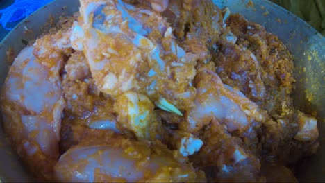 raw chicken pieces being marinated inside casserole pan by hand