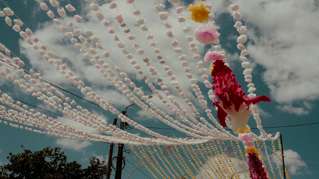 File di fili di perline rosa si irradiano da un nodo accanto a un nastro rosso sopra un palo di servizio al festival arraial.