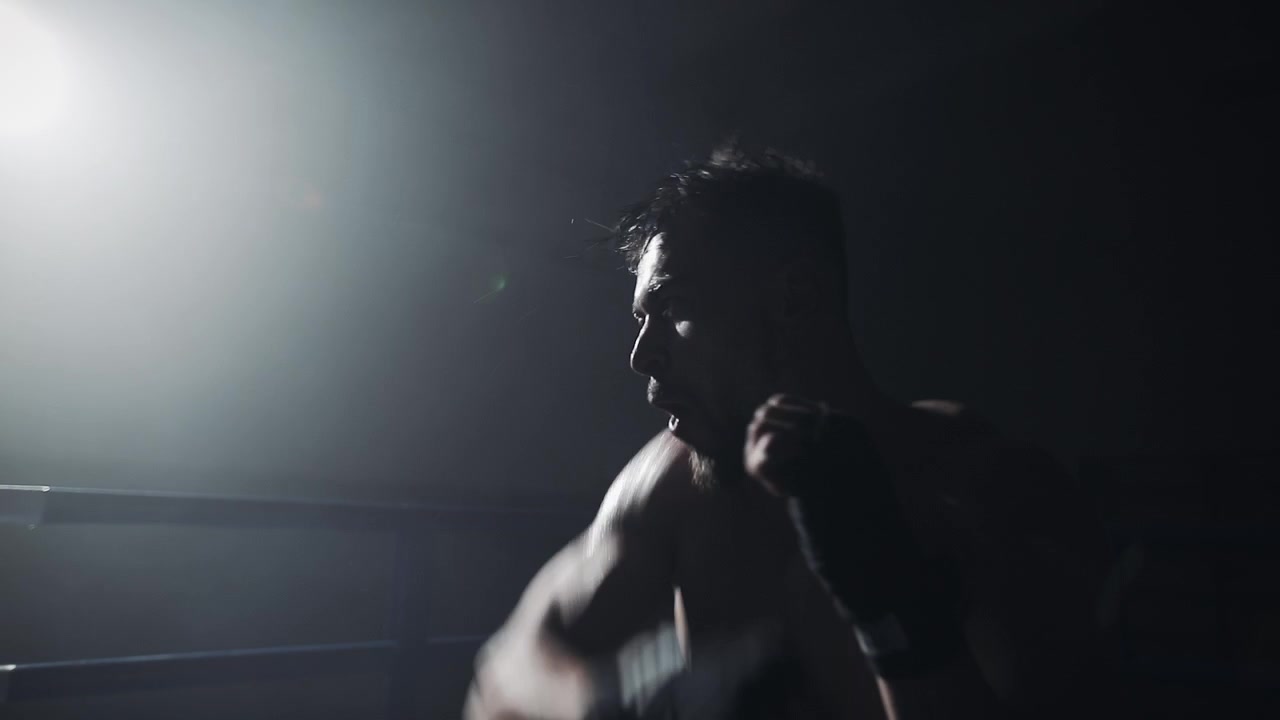 Man Shadow Boxing in a Dark Boxing Ring with Dramatic Lighting