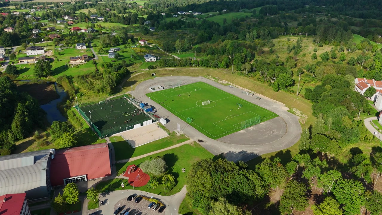 Talsi City Stadium And Players Playing On The Football Field In Talsi, Latvia. - aerial shot