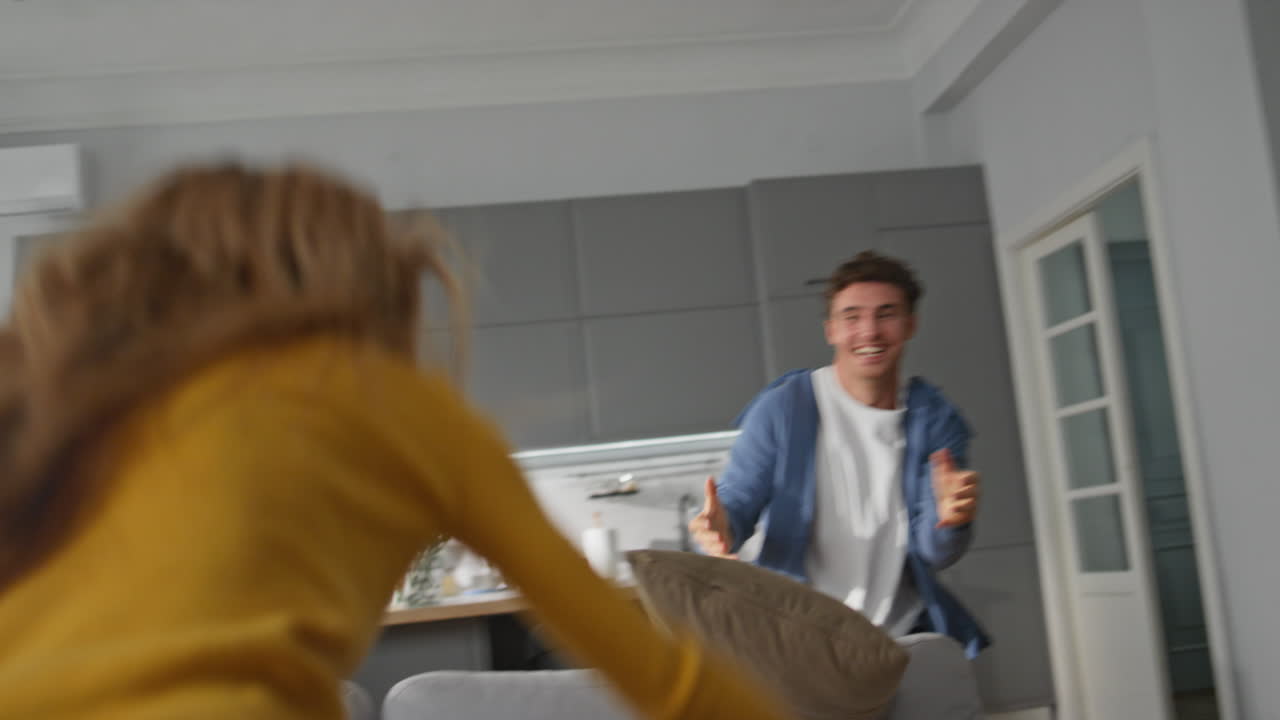 Closeup active spouses playing pillows living room together. Family having fun
