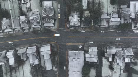 aerial tracking shot of american short school bus driving on small town streets during snow storm