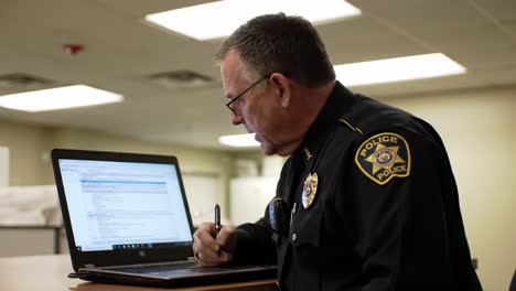 police officer reviewing documents on laptop