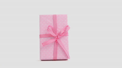 Hand-putting-down-pink-gift-wrapped-present-and-then-taking-it-away