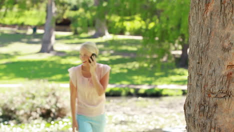 Eine-Frau-Geht-Auf-Einen-Baum-Zu-Und-Telefoniert