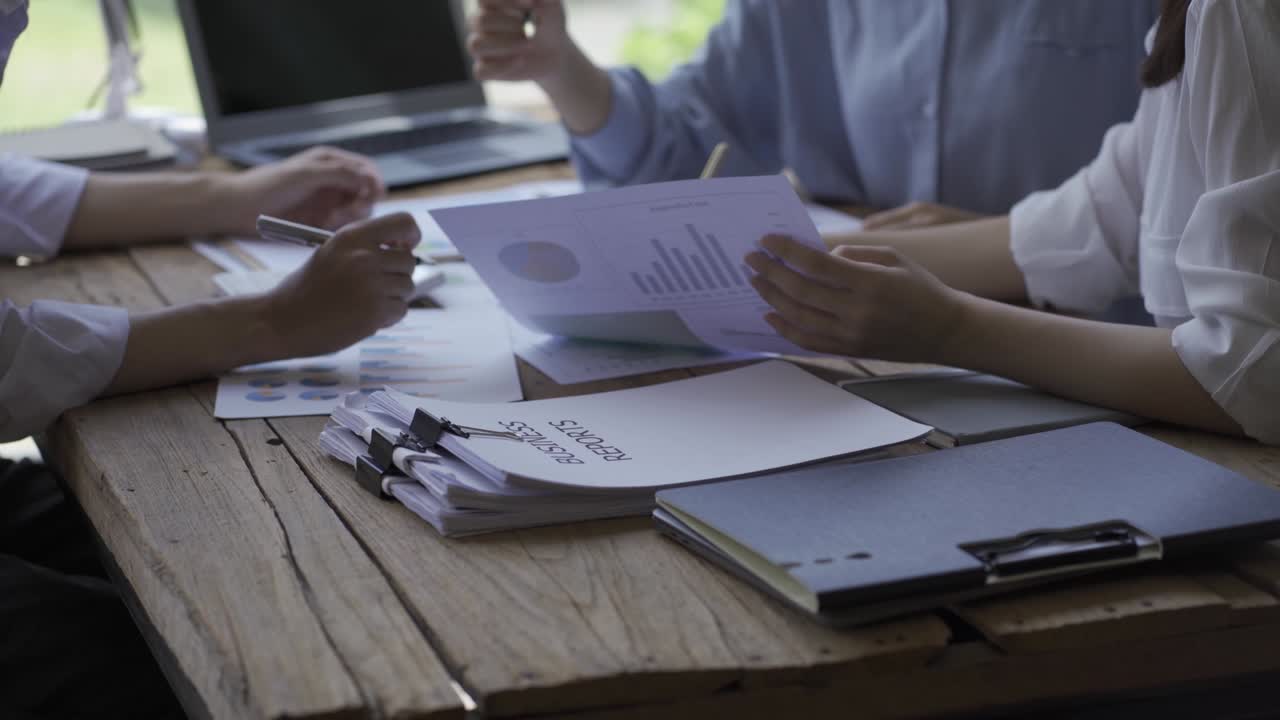 Happy Asian Business Woman Team Meeting Brainstorm Coworkers Project Finance Graph Document Work Together Strategic Planning For Success Enjoy working as a team in the office.