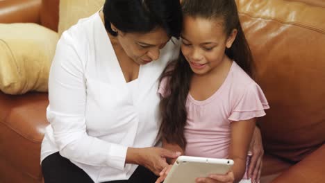 Grandmother-and-granddaughter-using-digital-tablet-in-living-room-4k