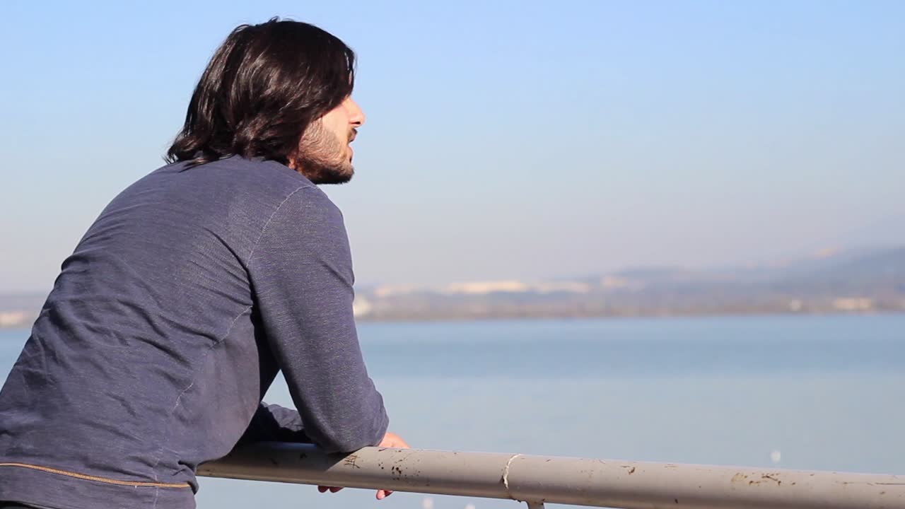 외로운  ⁇ 만적인 남자가 바다를 바라보며 휴식을 취합니다.