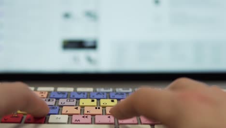 slow motion: typing on editing keyboard in front of modern display