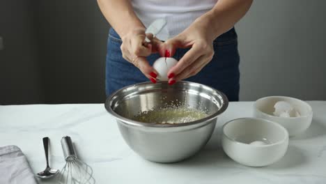 woman baking a cake - adding an egg to batter