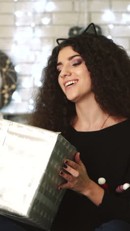 gift box new year day celebration. young attractive woman with gift box near fireplace vertical video